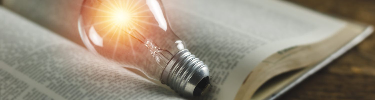 Książka z zapaloną żarówką symbolizująca leksykon termoizolacji od PureEnergy